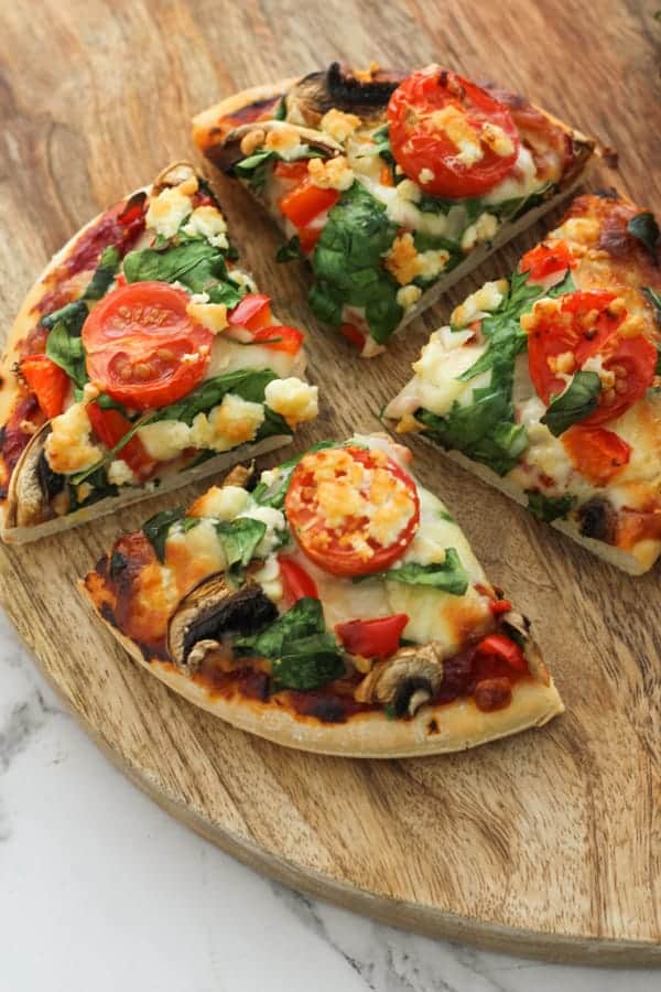 pizza cut in quarters on a wooden board.