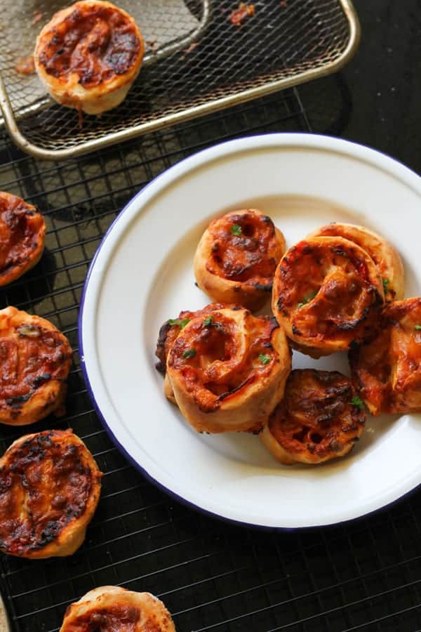 pizza pinwheels piled up on a white plate.