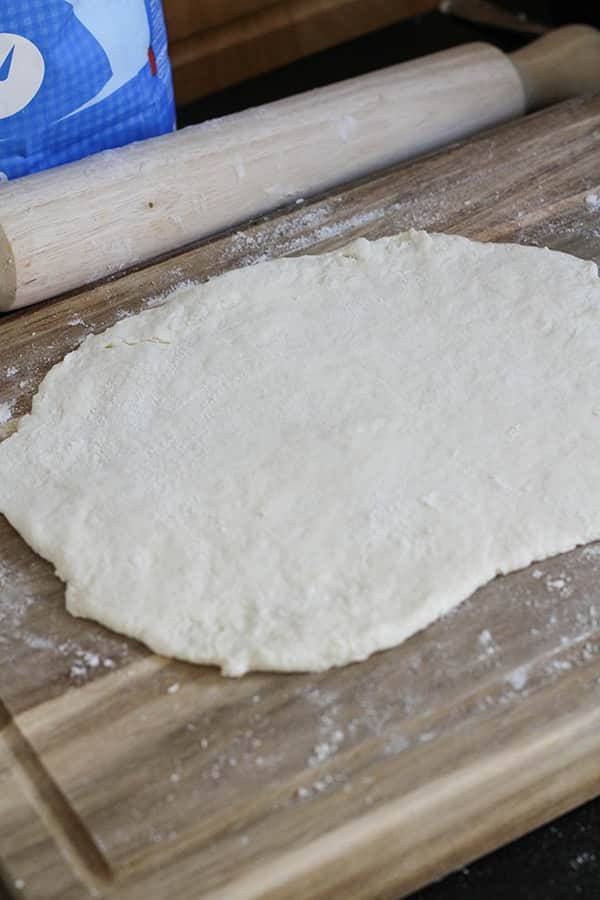 two ingredient dough rolled out on a wooden board.