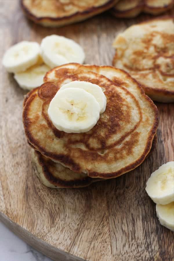 pikelets stacked on top of each other on a wooden board.