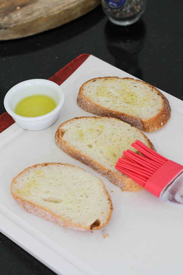 a pastry brush brushing oil over slices of bread. 