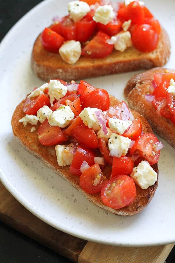 tomato and feta bruschetta on a white plate.