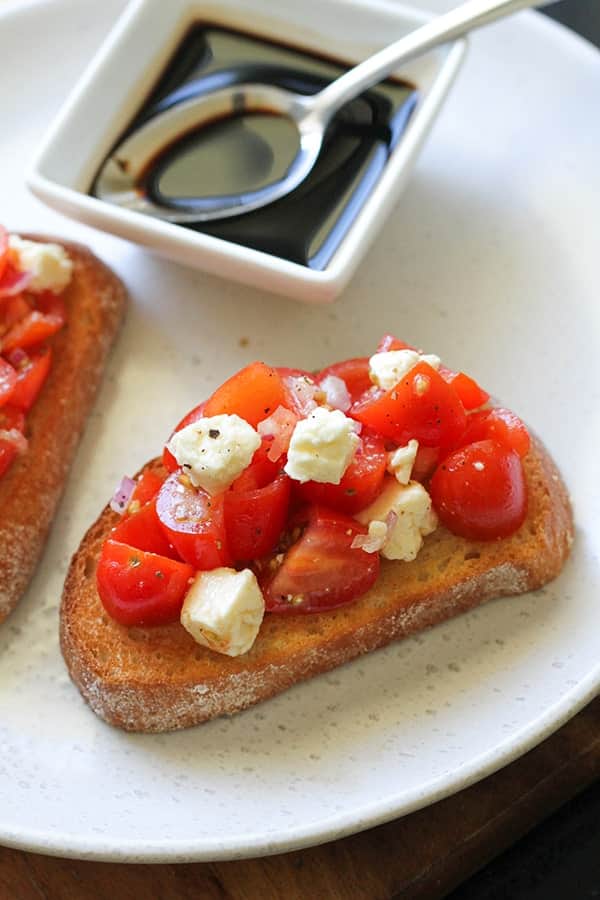 tomato and feta bruschetta on a white plate.