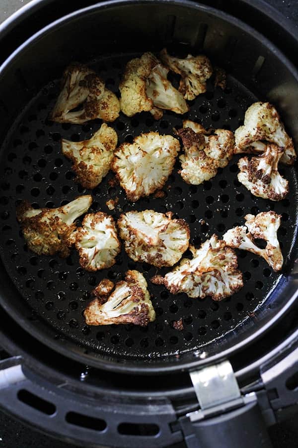 roasted cauliflower in an air fryer basket.