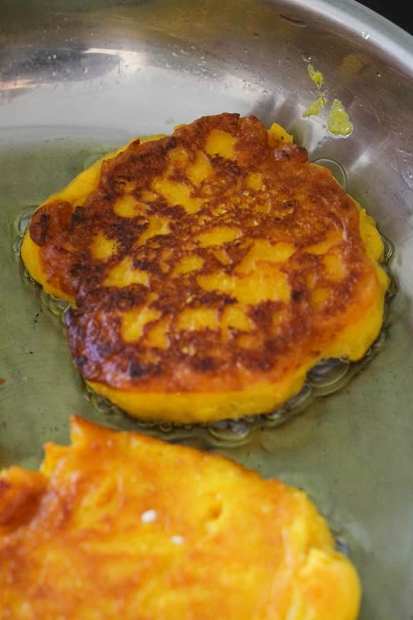pumpkin fritter being cooked in a frying pan.