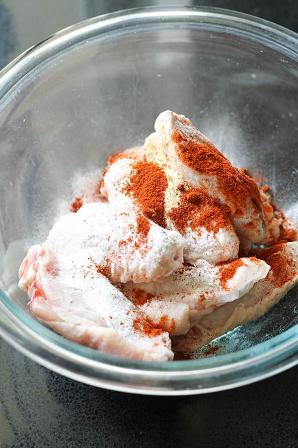 chicken wings in a bowl with baking powder and spices.
