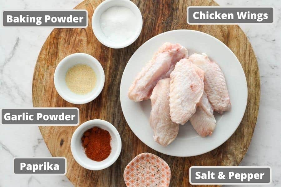 chicken wing ingredients on a wooden board, including baking powder, garlic powder etc.