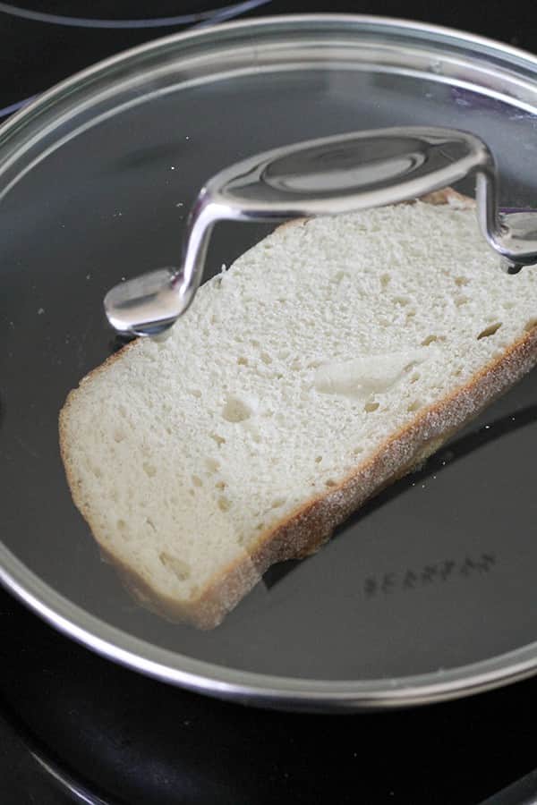 slice of bread in a skillet with a lid on top.