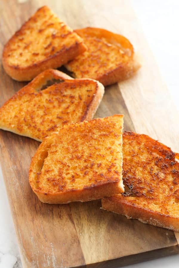 slices of cheese toast on a wooden serving board.