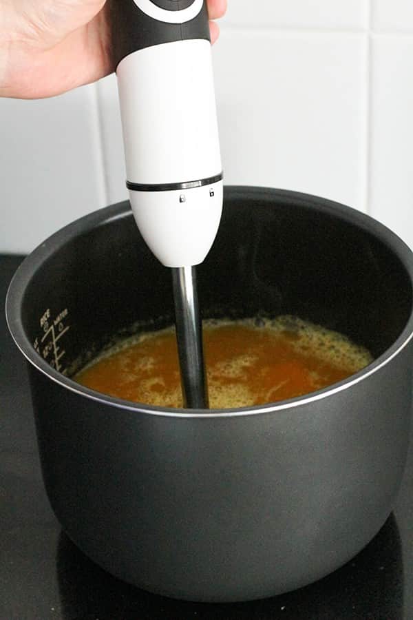 a stick blender blending soup in a pot.