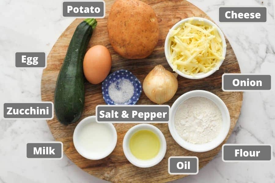 ingredients for potato fritters on a wooden board including egg, cheese and milk.