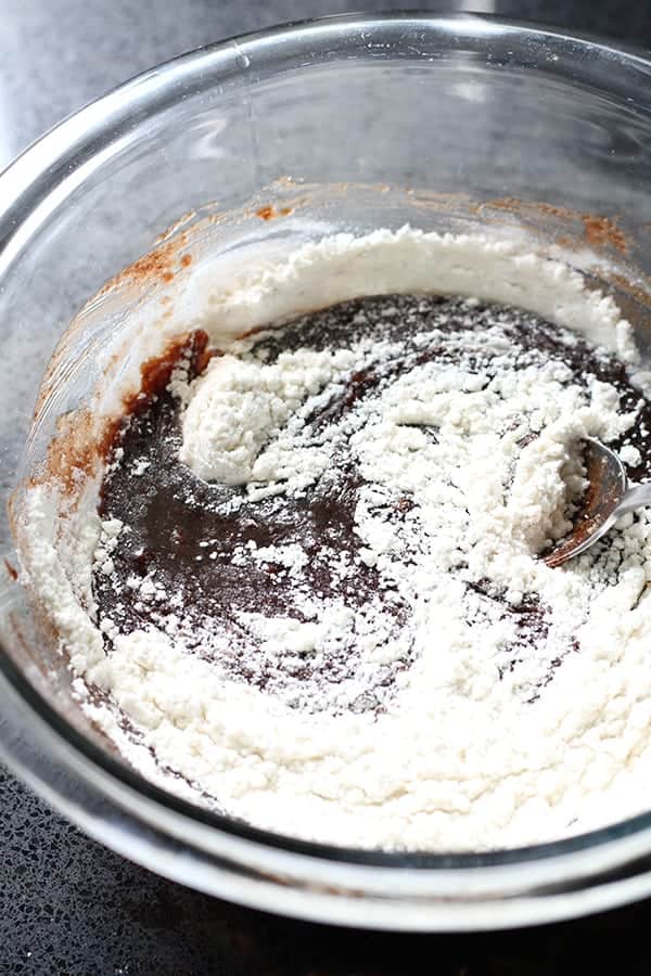 brownie mixture covered in flour in a glass bowl.