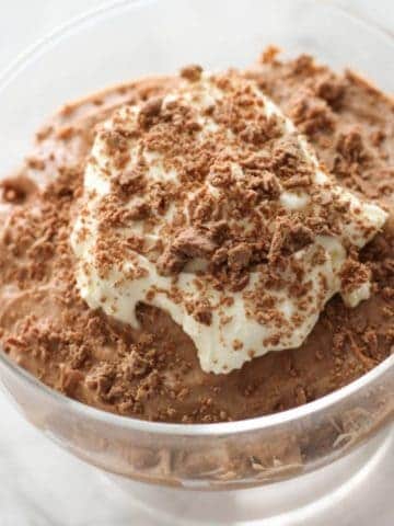 chocolate mousse in a glass topped with whipped cream and grated chocolate.