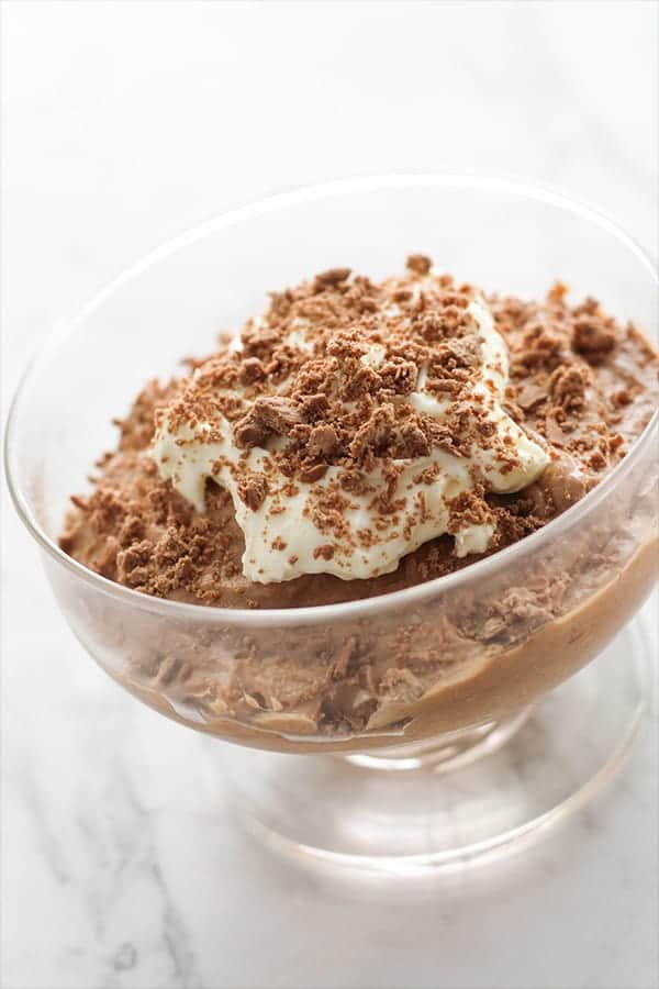 chocolate mousse in a glass topped with whipped cream and grated chocolate.