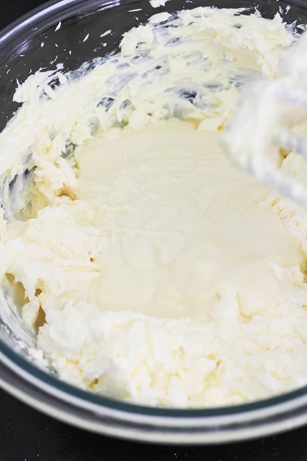 white chocolate mixed with cream cheese and sugar in a mixing bowl.