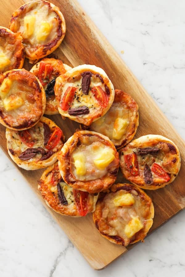 mini puff pastry pizzas on a wooden board.