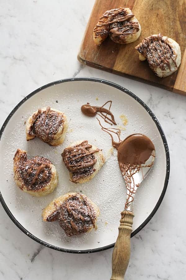 pinwheels on a white plate drizzled with chocolate.