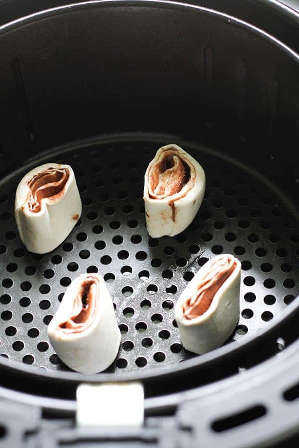 uncooked pinwheels in an air fryer basket.