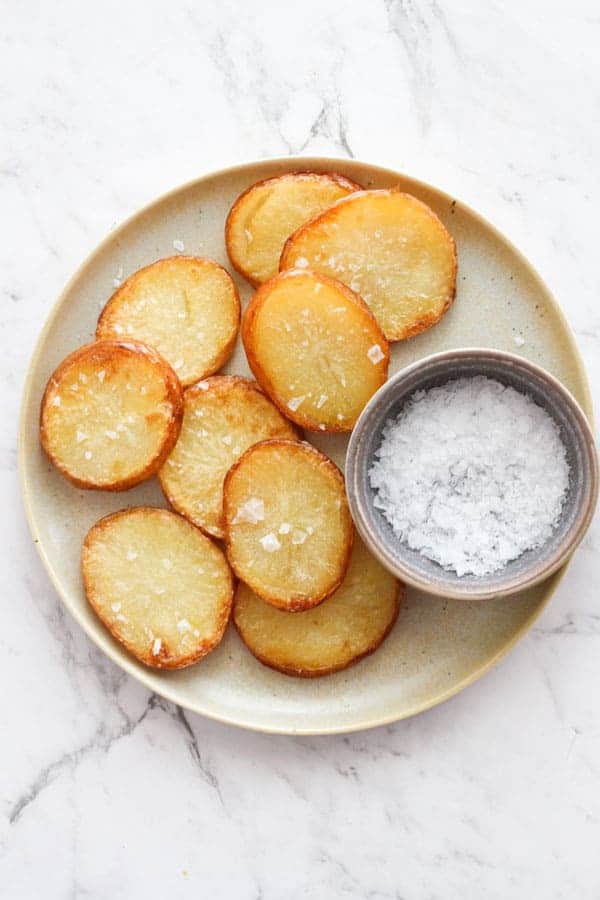 salt and vinegar potatoes on a plate with a serving bowl of salt.