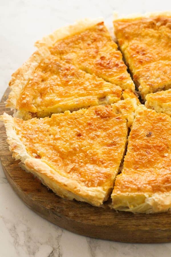 bacon and egg pie sliced on a wooden board.