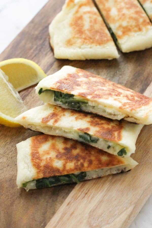 slices of spinach and feta gozleme on a wooden board.