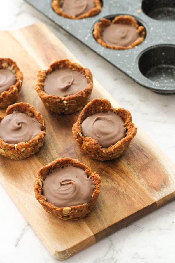 mini caramel tarts on a wooden board.