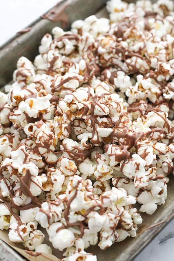 popcorn drizzled with chocolate on a baking tray.