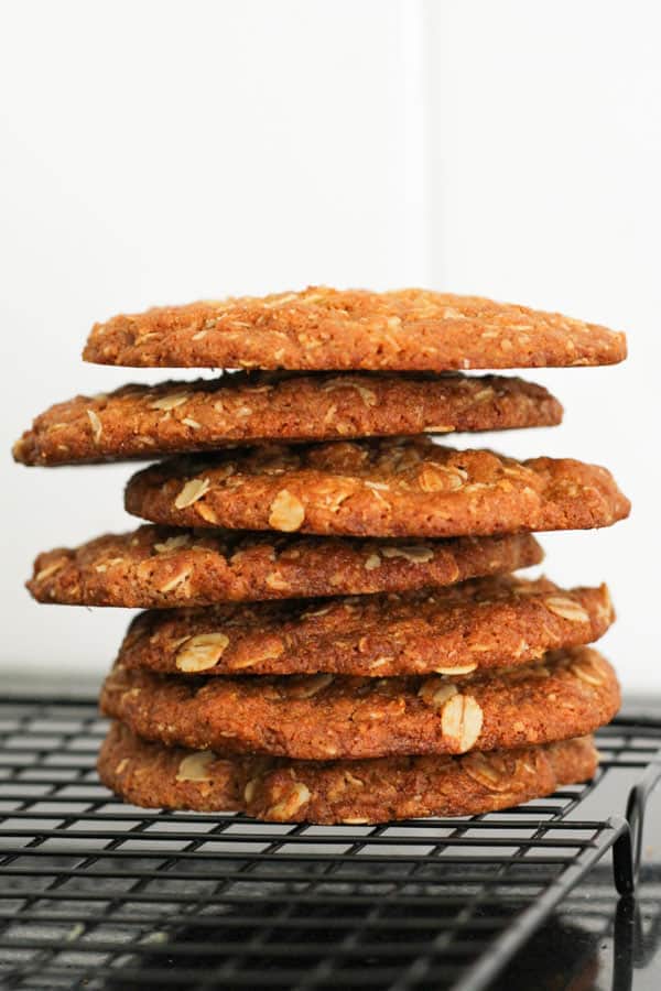 crunchy anzac biscuits stacked on a wire rack.
