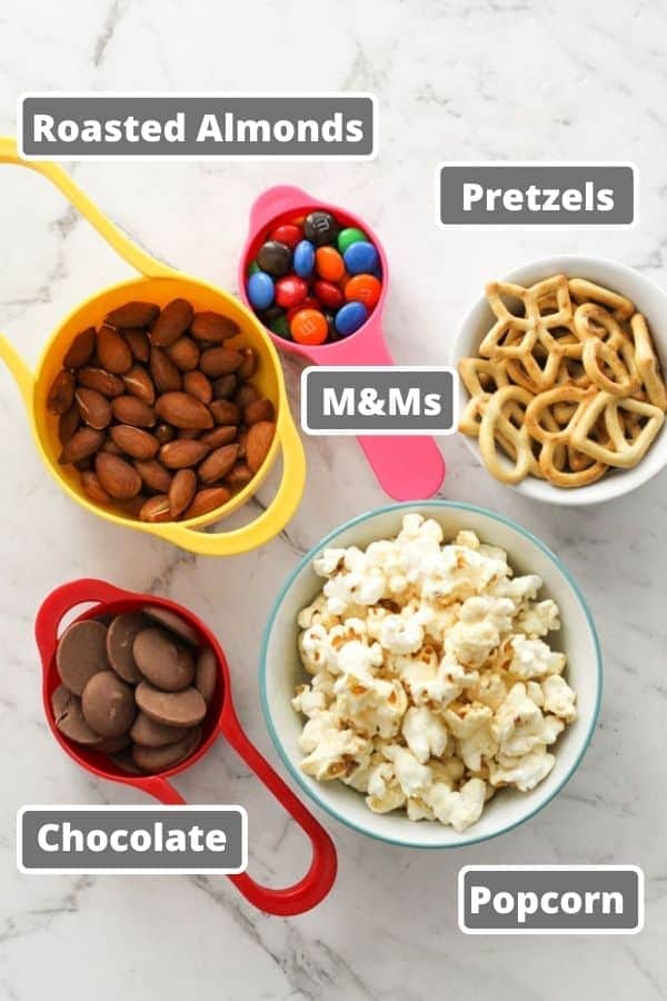 popcorn trail mix ingredients on a white marble background.