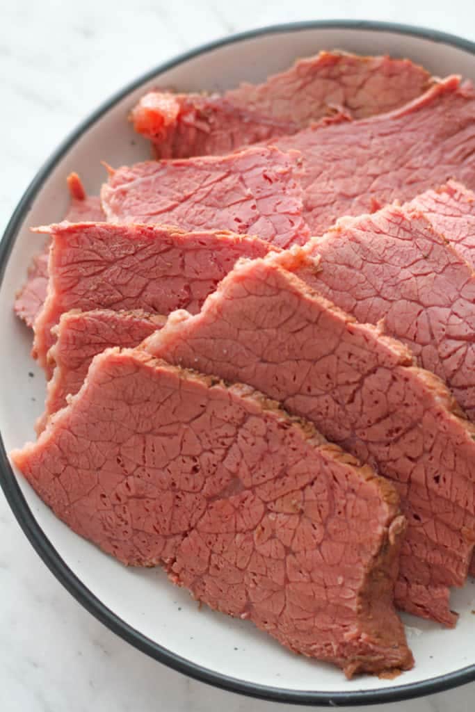 slices of corned beef on a white plate.