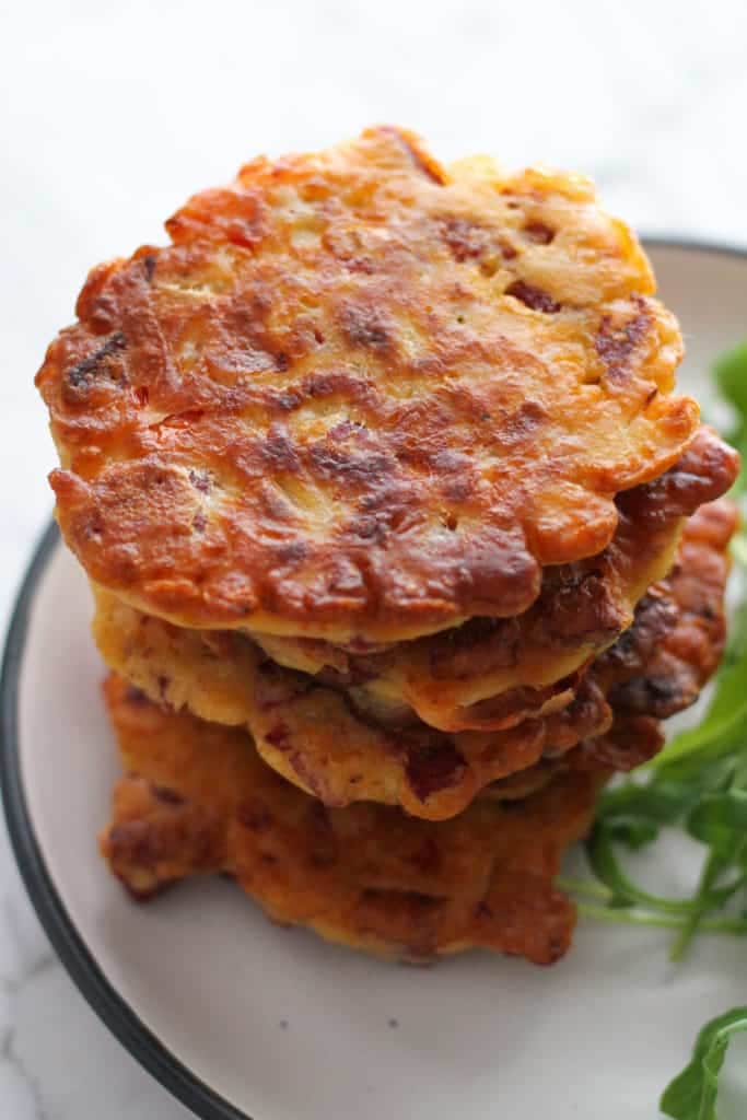 fritters stacked up high on a white plate.