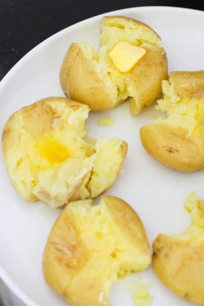 potatoes on a white plate topped with butter and salt.