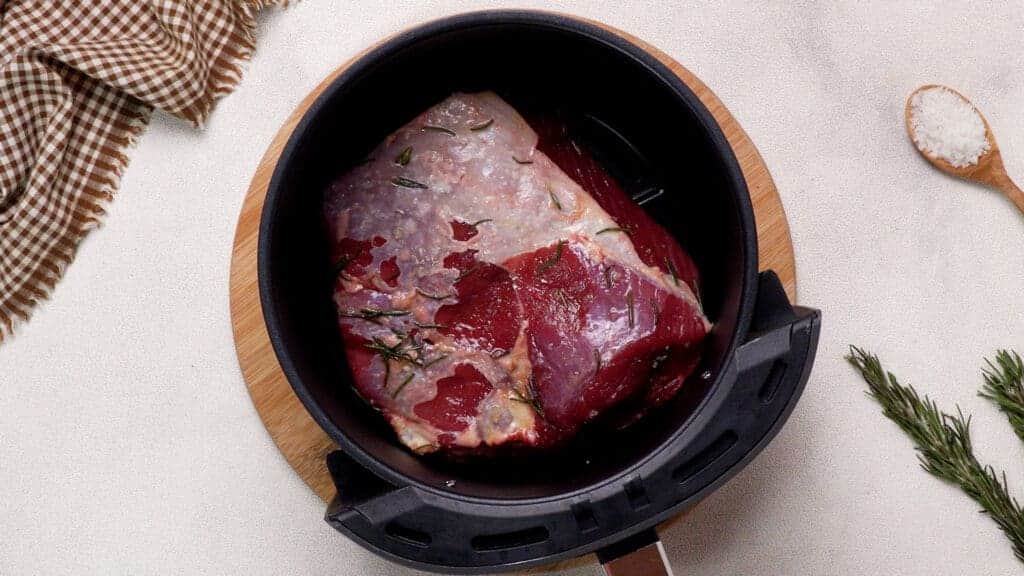 Beef seasoned with oil-herb mixture in the ninja air fryer basket