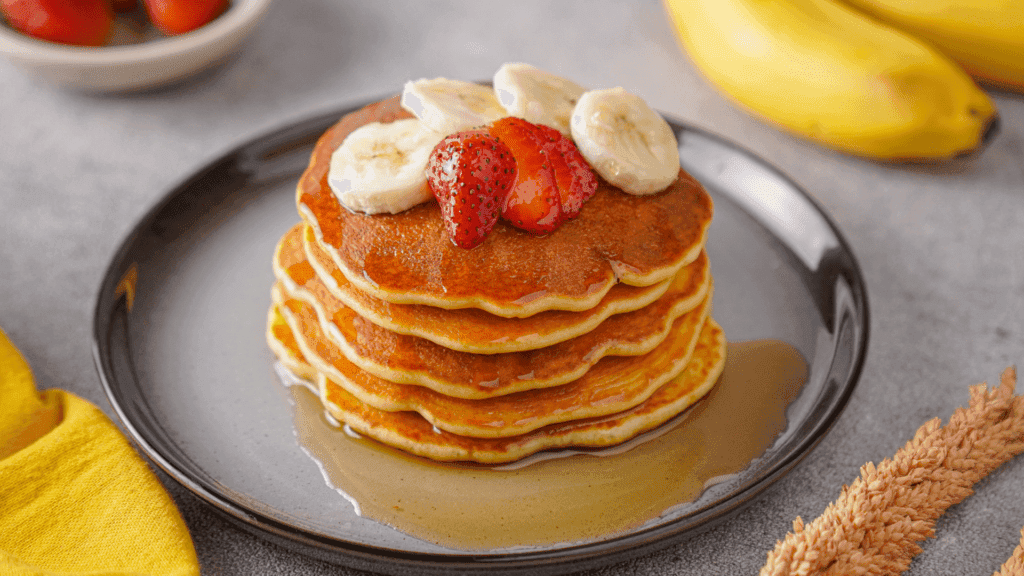 Protein Pancake with banana, strawberries and maple syrup toppings on the plate