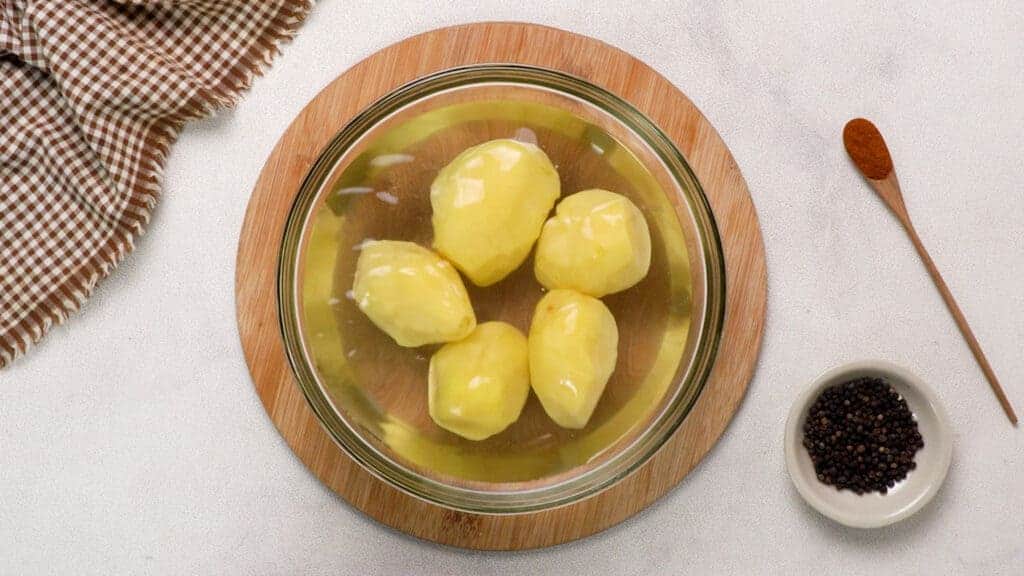 Peeled potatoes in the bowl of water