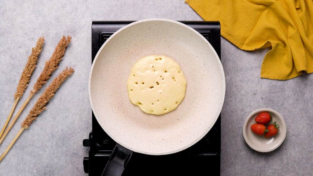 Protein pancakes with tiny bubbles on non-stick pan