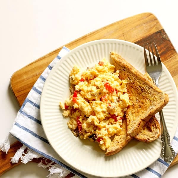 Easy scrambled eggs with veggies and two pieces of toast on a white plate