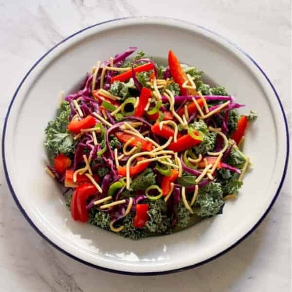 crunchy kale salad with lemon tamari dressing on a white plate