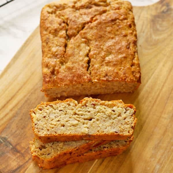 slices of healthy banana bread stacked on top of each other with the loaf sitting behind