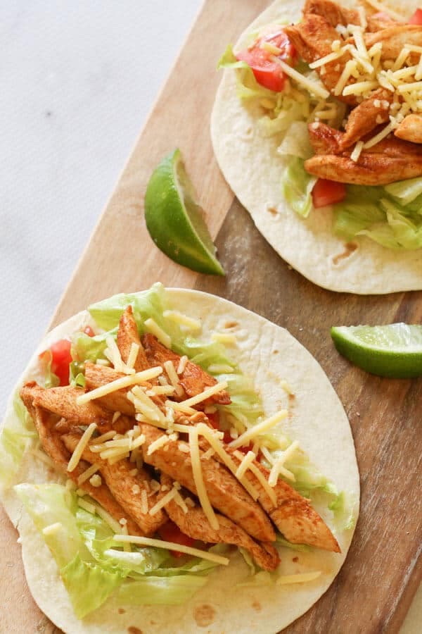two chicken tacos on a wooden board