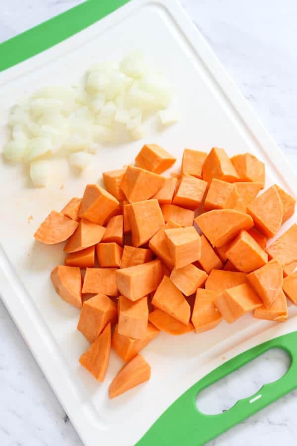 diced sweet potato and onion on a white cutting board