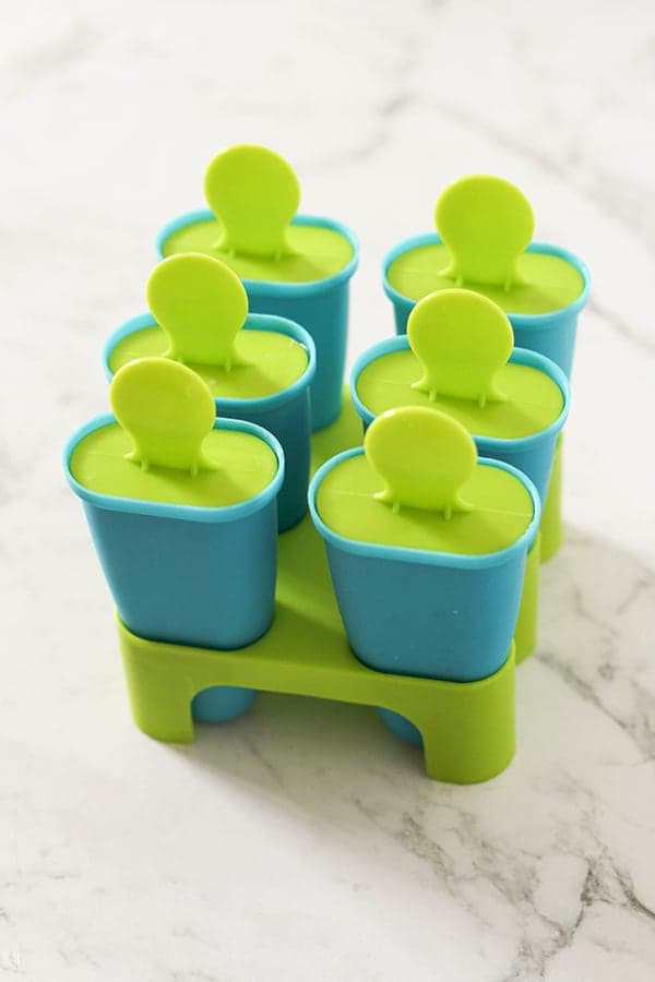 popsicle moulds on a white marble background.