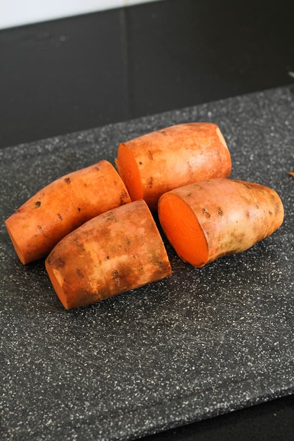 a sweet potato cut in halves on a cutting board.