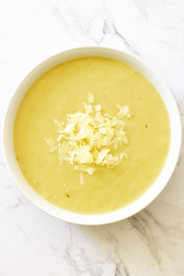Potato and Leek Soup in a white bowl topped with shredded cheddar cheese.