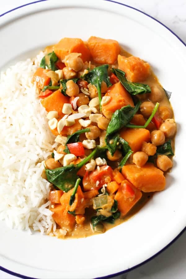 close up of sweet potato, chickpea and spinach curry in a bowl with rice