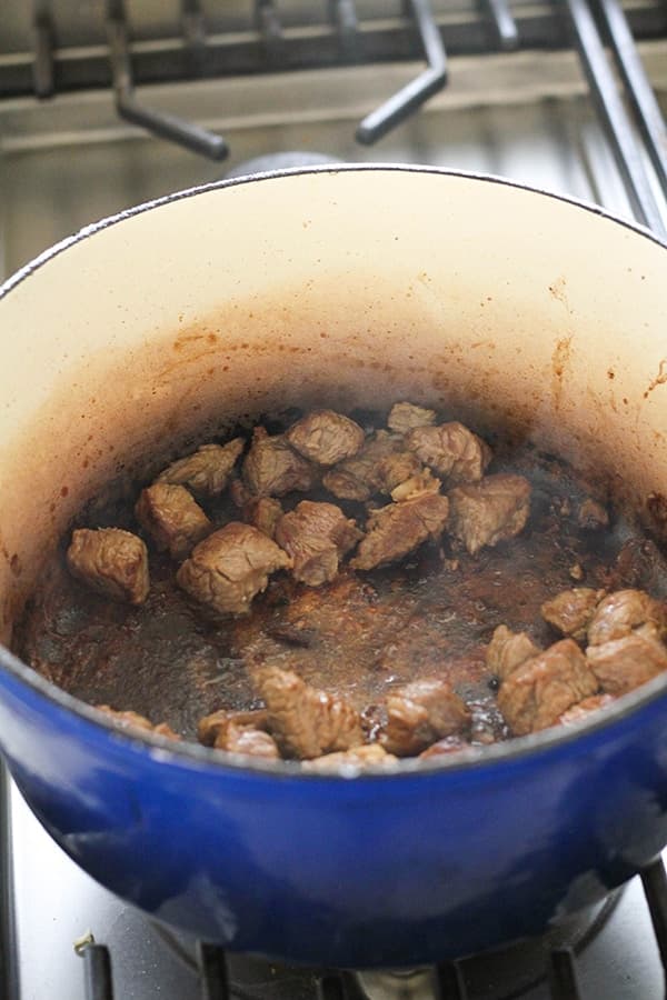beef browning in a blue dutch oven.