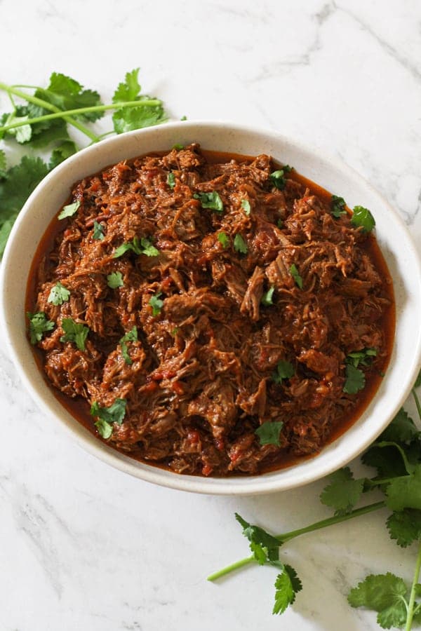 shredded mexican beef in a white bowl.