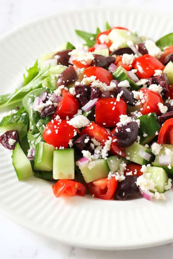close up image of a greek salad on a white plate