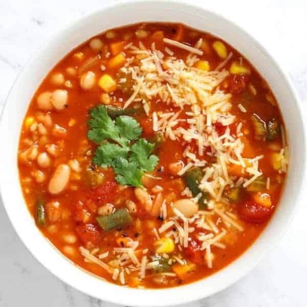 vegetable barley soup topped with parmesan cheese and coriander