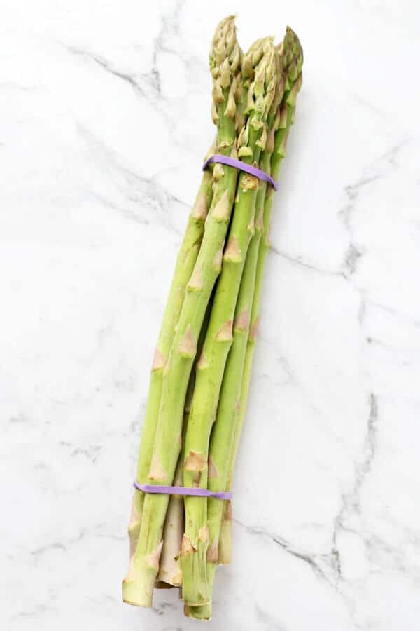 a bunch of asparagus on a white marble background
